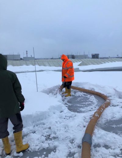 Arbeiter saugt Schnee von Flachdach