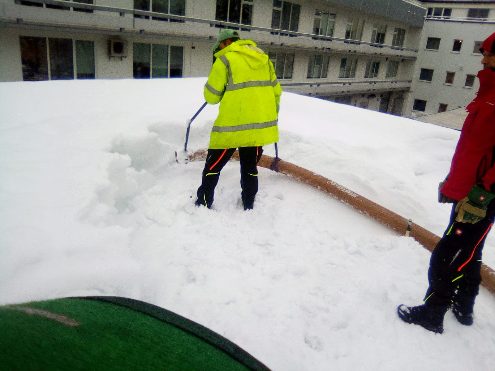 Ein Arbeiter saugt Schnee vom Dach eines Hauses
