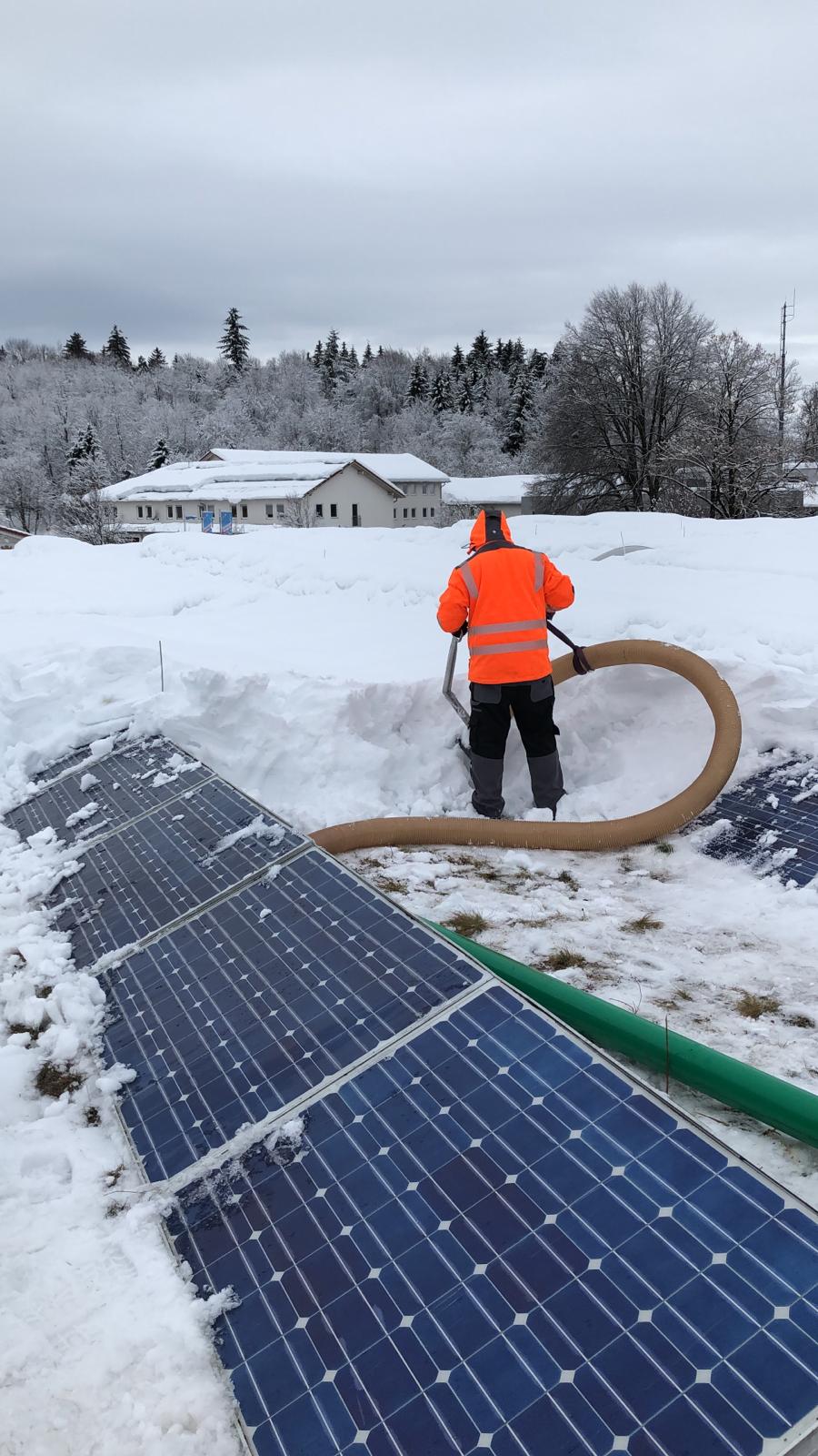Arbeiter saugt Schnee von einem Flachdach